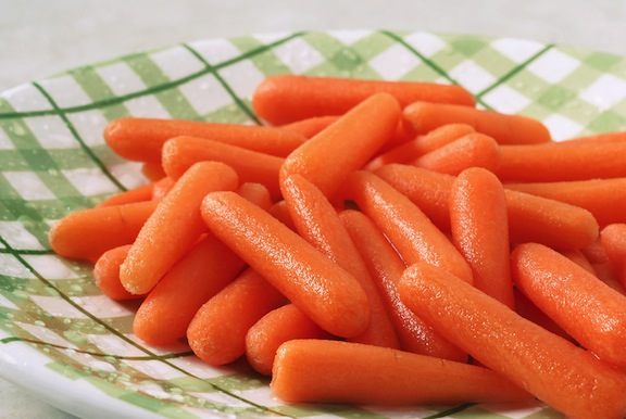 Freshly washed baby carrots on a green plaid, ceramic plate.  Close-up with shallow dof